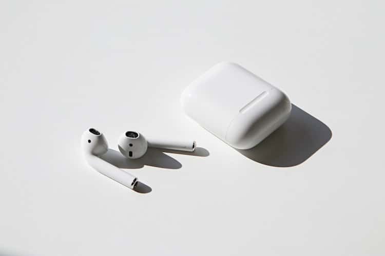 Right and Left apple airpod earbuds next to airpod case
