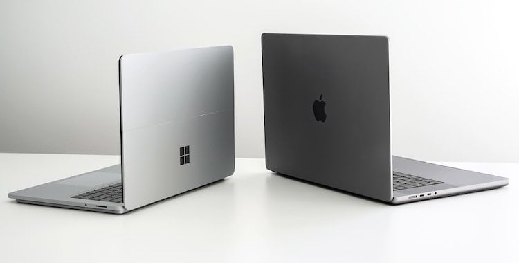 windows laptop and macbook laptop on white surface